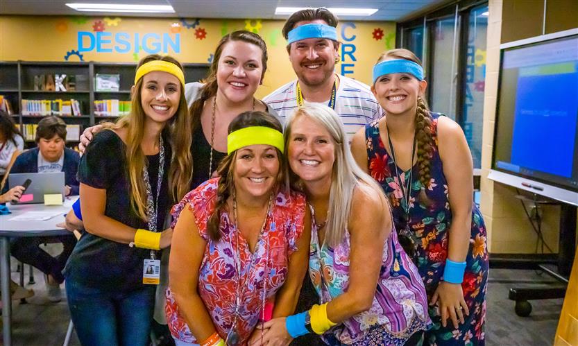 Teachers pose while wearing neon sweatbands
